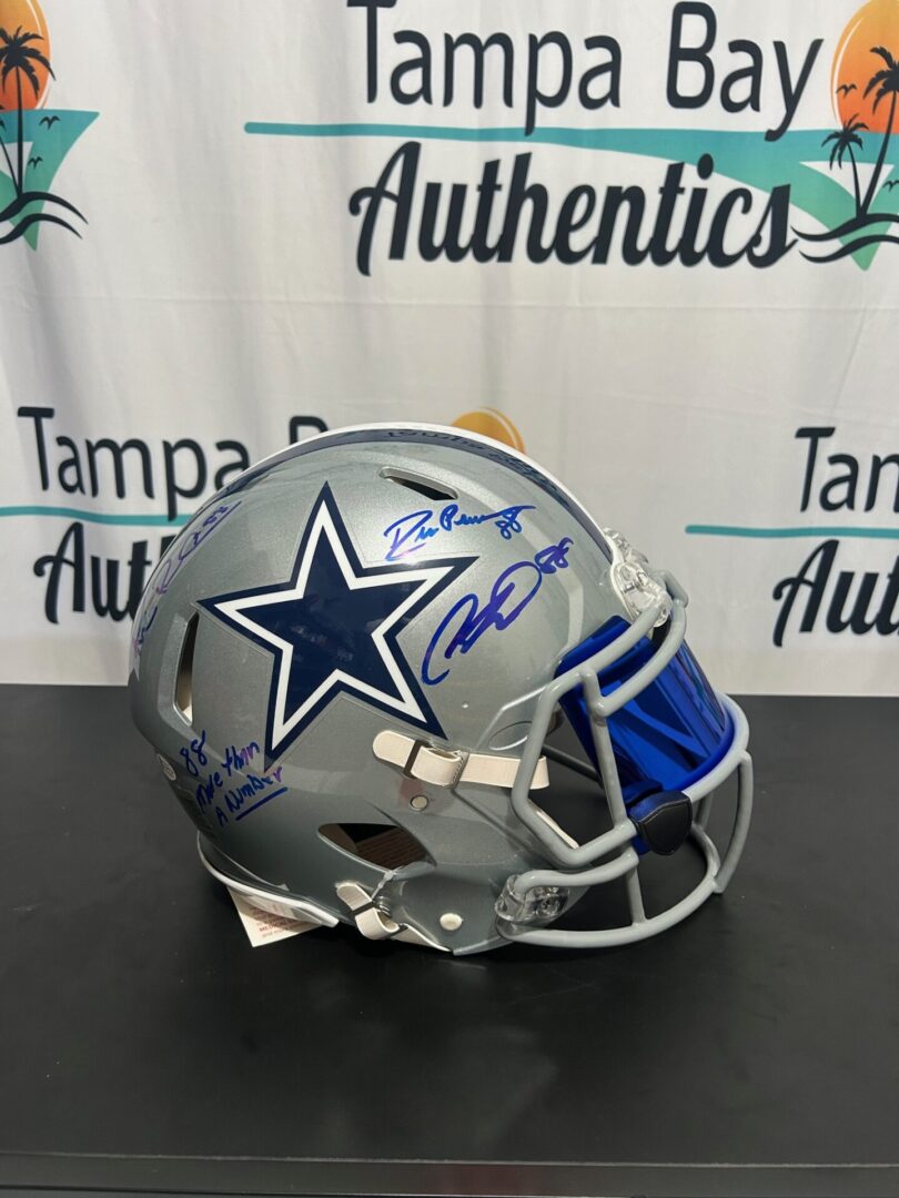 A Dallas Cowboys football helmet with a blue faceguard and signatures.