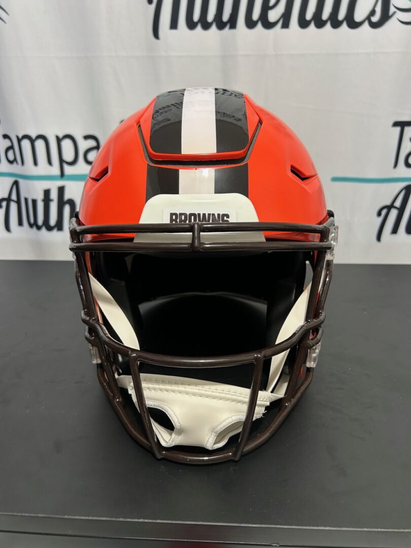 Front view of a red football helmet with a white stripe and black facemask.