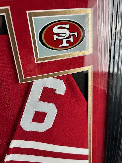 A framed red sports jersey with the number 6 and San Francisco 49ers logo.