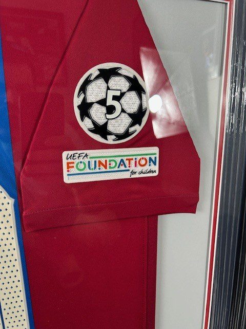A red jersey with a 5-year foundation patch and a black and white soccer ball logo.