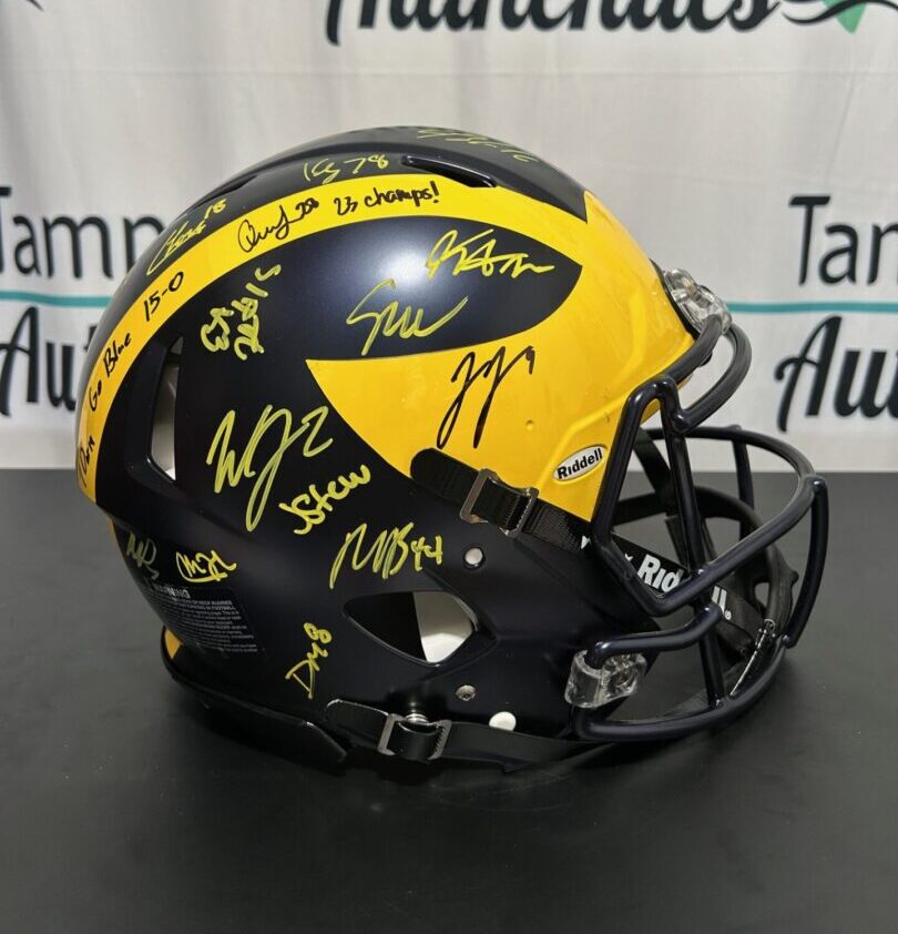Black and yellow football helmet with multiple signatures.