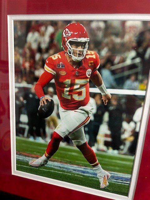 Kansas City Chiefs player running with football on the field.