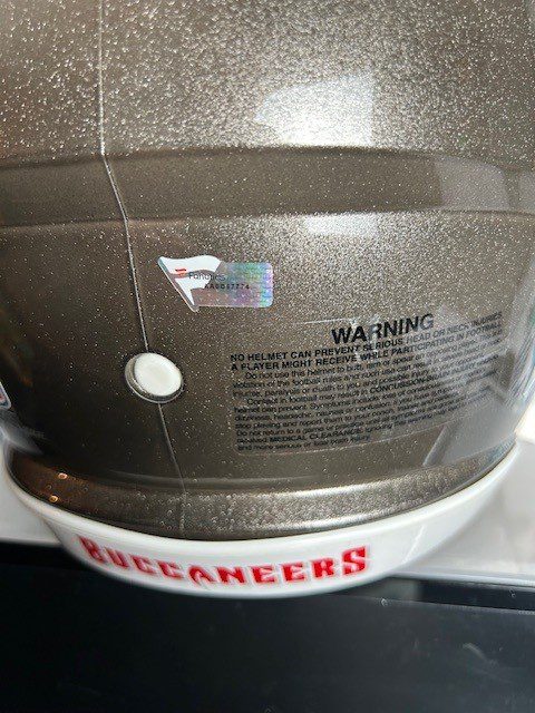 Close-up of a Tampa Bay Buccaneers football helmet with a warning label.
