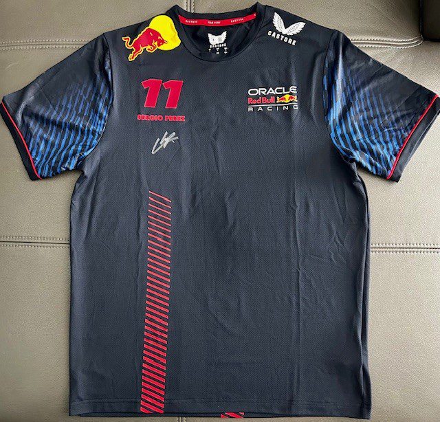 A black Red Bull racing team shirt with logos and signatures.