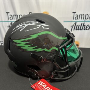 Black football helmet with green visor, autograph.