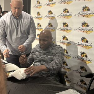 A man signing an autograph at an event booth.